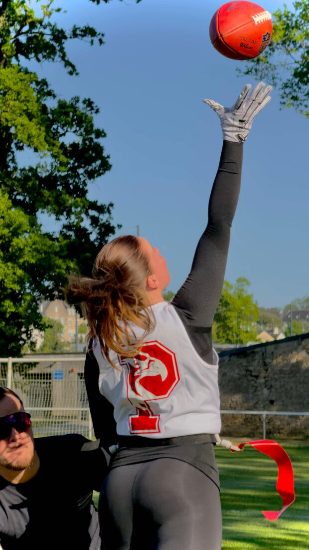 Image d'une femme tendant la main vers un ballon pour l'attraper pendant qu'un joueur essaie de la déflaguer
